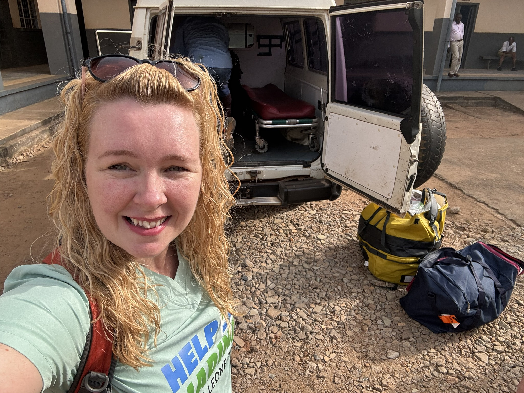 Amanda in Sierra Leone - pictured with a vehicle with a medical trolley inside behind her