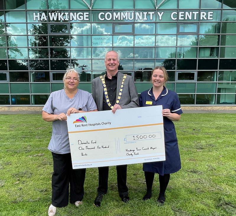 Ann McGovern and Amy Harris receive the cheque from the current Mayor, Chris Johnson. They are pictured outside Hawkinge Community Centre