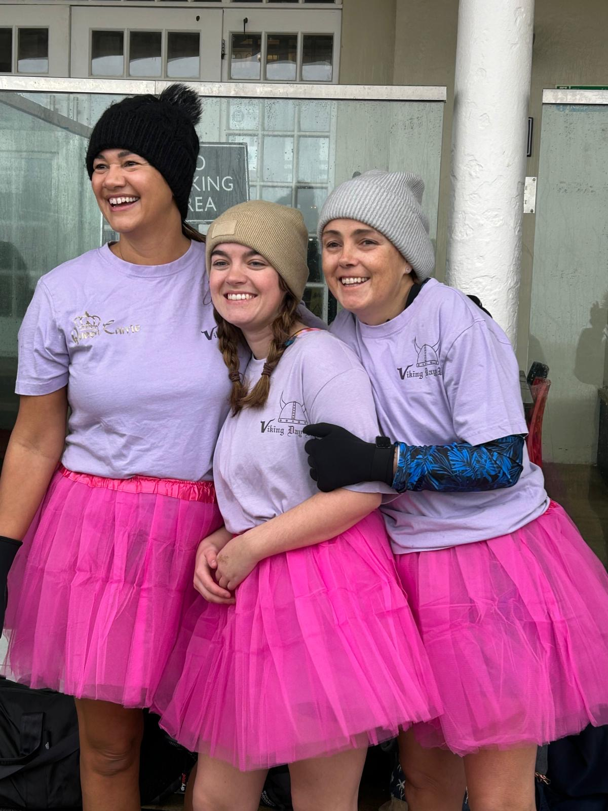 Carrie, Izzy and Kerry before the dip. They are wearing pink tutus, purple t-shirts and woolly hats