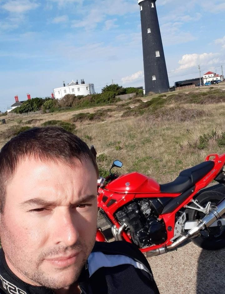 Gavyn Mills, pictured with a motorbike in front of a lighthouse