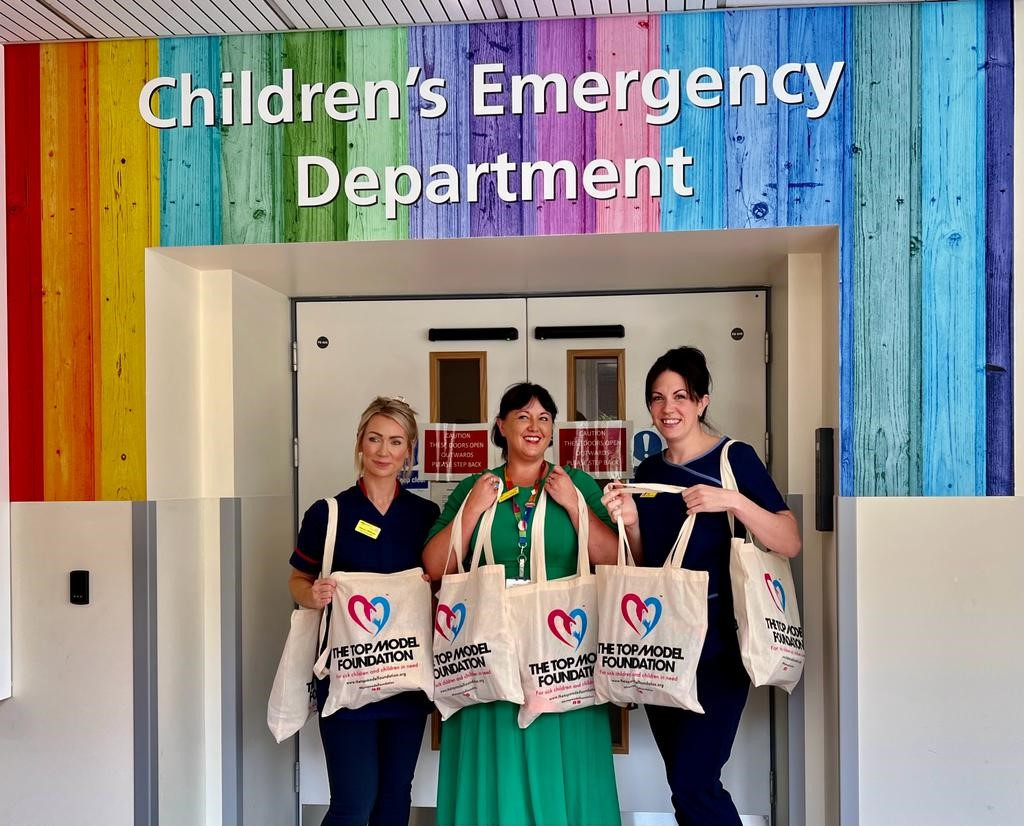 Jo Williams, Dee Neligan and Cat Miller with some of the bags. They are standing in front of the colourful entrance to the children's emergency department