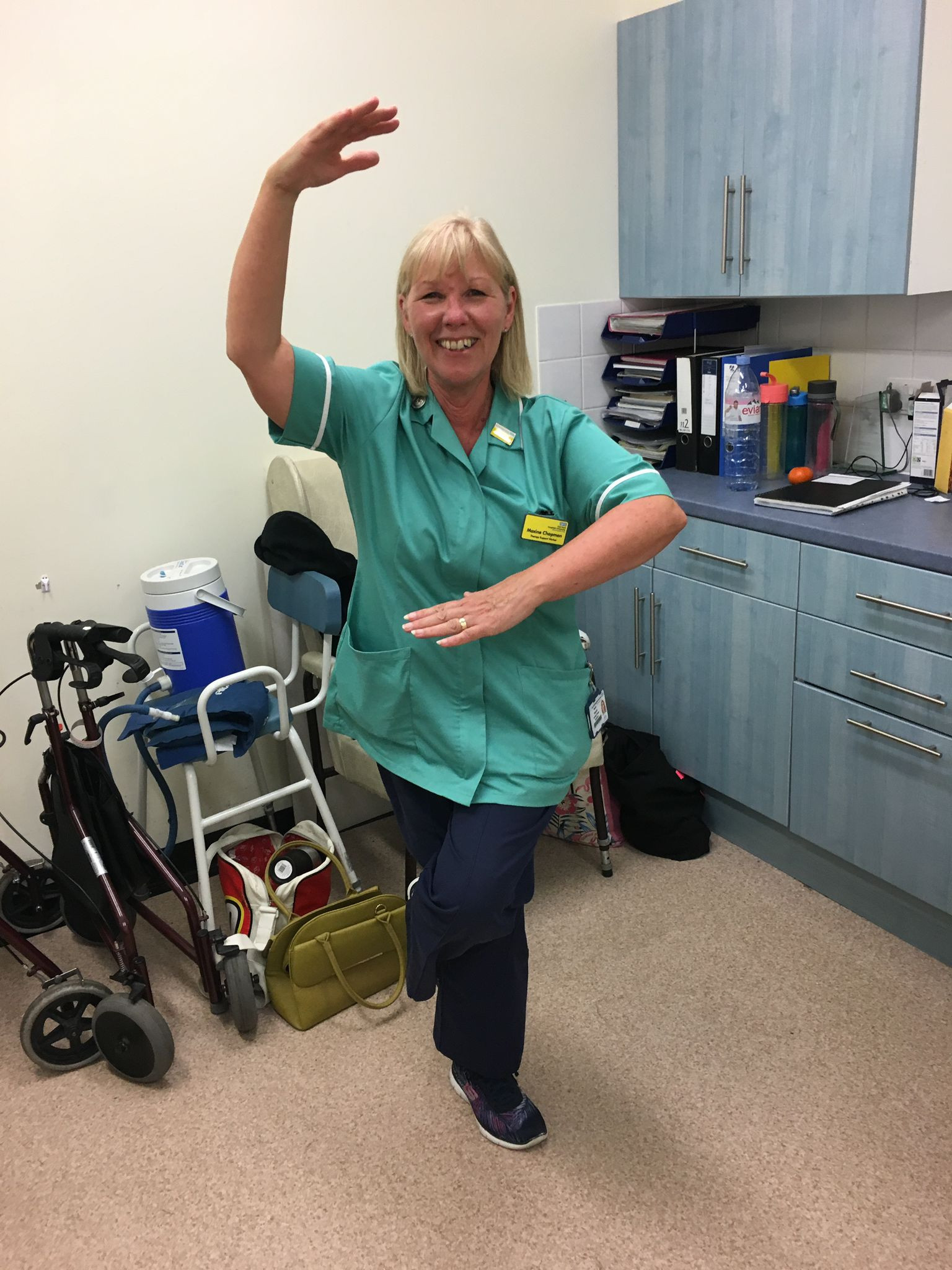 Maxine Chapman, who is retiring after more than 30 years. She is pictured in a staffroom striking a balletic pose with medical equipment behind her