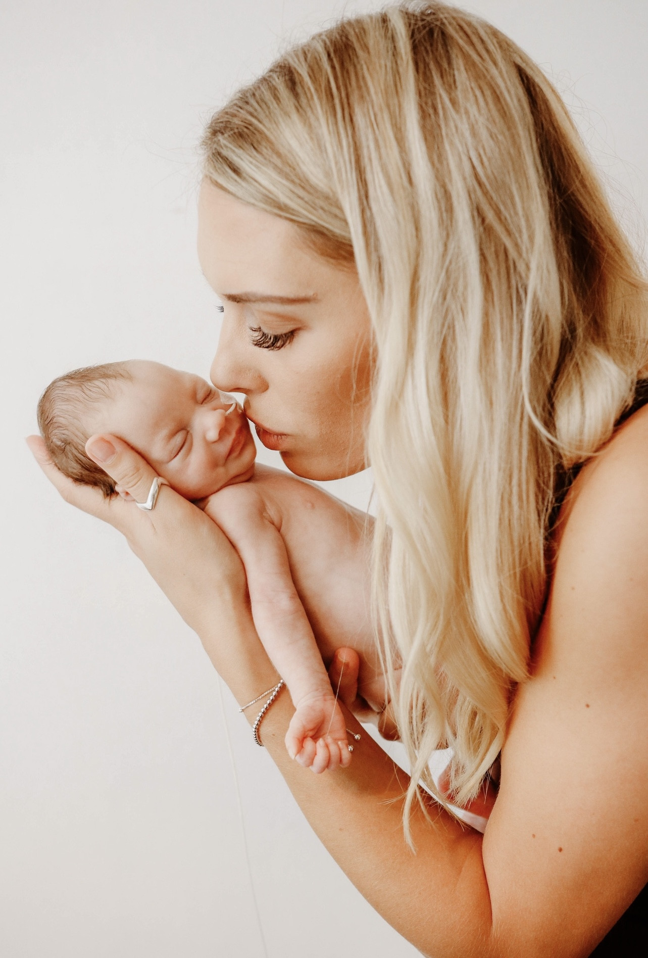 Mum Mel with baby Gracie. She is holding her in her arms and kissing her face.