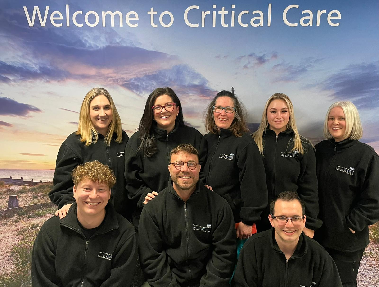 The team who will take on the 3 Peaks challenge, wearing black fleeces pictured in front of a Welcome to Critical Care sigh