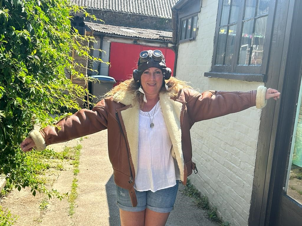 Wendy Carn, who is taking on a wing walk in July for East Kent Hospitals charity. She is pictured outside wearing a Biggles-style coat and hat with goggles with her arms out to illustrate aeroplane wings