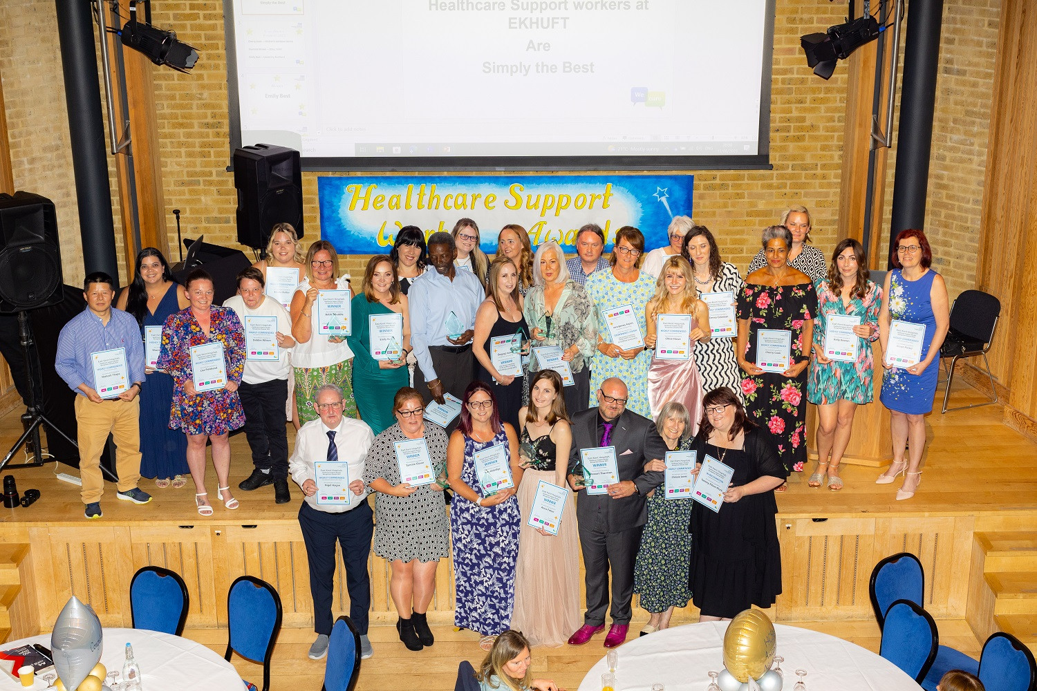 Group photo of the winners and finalists from the Healthcare Support Workers Awards - image shows a group of people on a stage holding certificates and awards