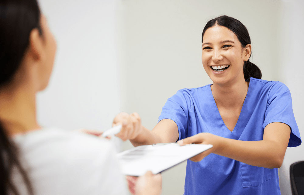 Nurse hands papers and pen to a patient