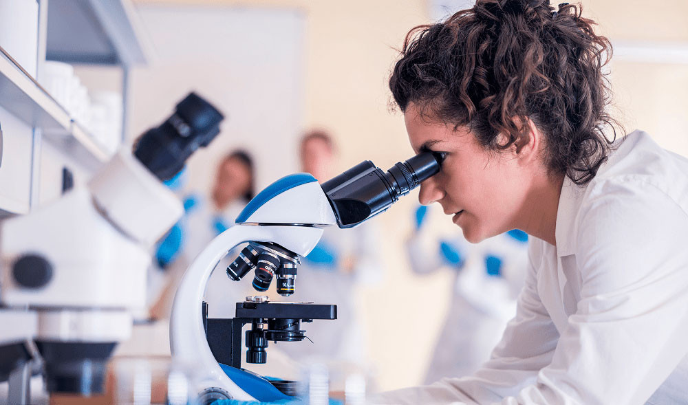 Woman in a laboratory looks through a microscope